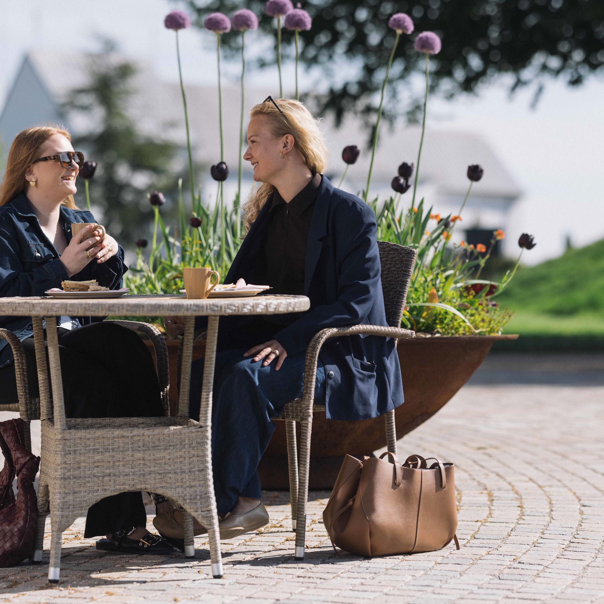 To kvinder sidder ved et bord, drikker kaffe og snakker.